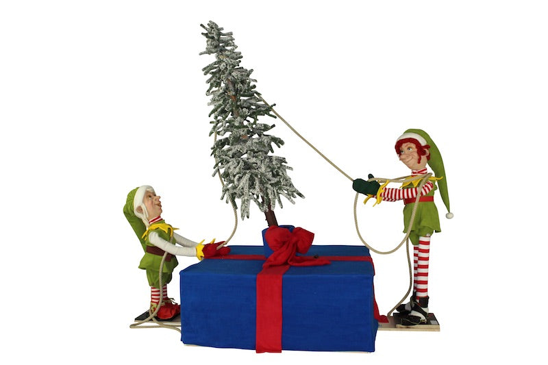 Weihnachtselfen richten einen Baum auf.