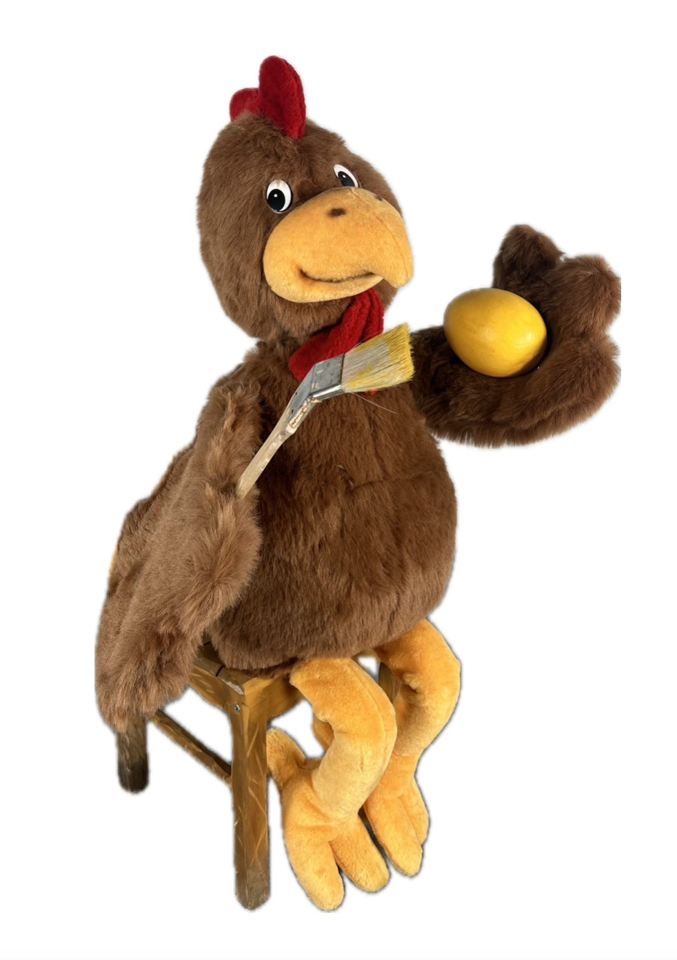 Huhn sitzend auf Hocker bemalt Ei mit gelber Farbe.