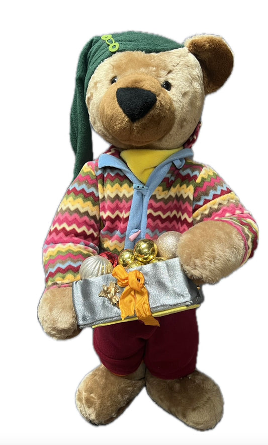 Teddybär mit grüner Mütze und Geschenkpaket mit Kugeln
