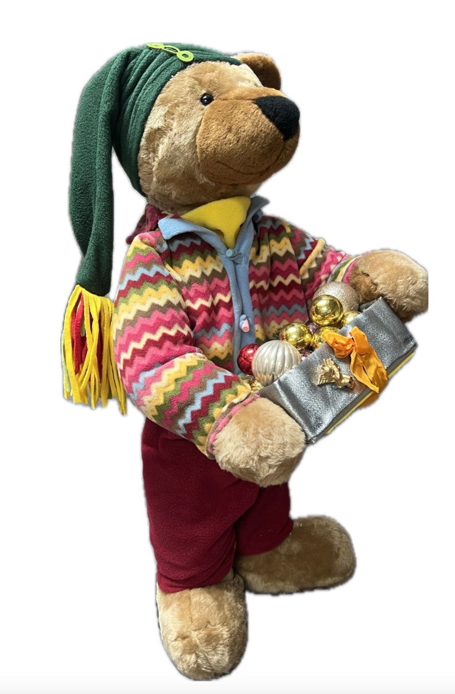 Teddybär mit grüner Mütze und Geschenkpaket mit Kugeln