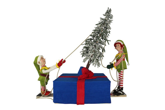 Weihnachtselfen richten einen Baum auf.