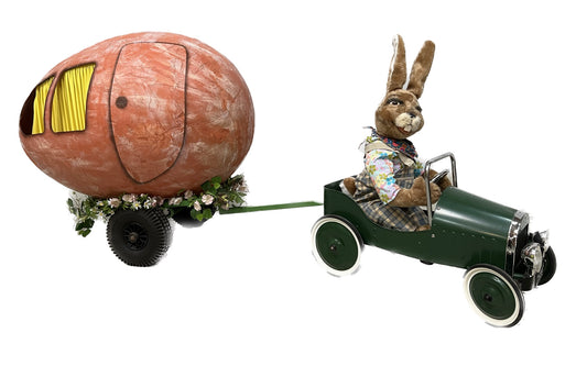 Hase mit Tretauto und Wohnanhänger als Ei