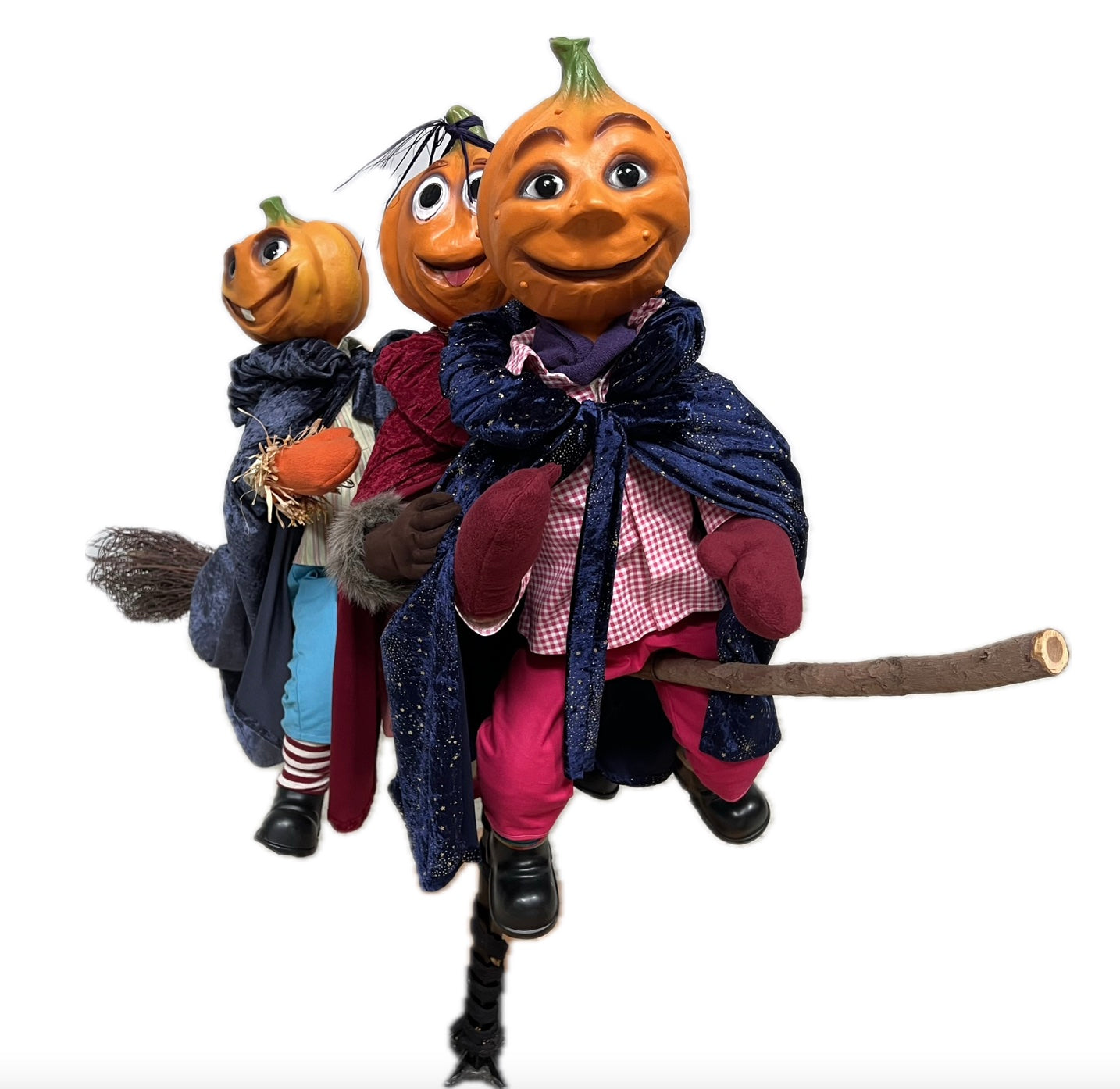 3 Kürbisfiguren fliegen auf einem Hexenbesen