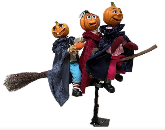 3 Kürbisfiguren fliegen auf einem Hexenbesen