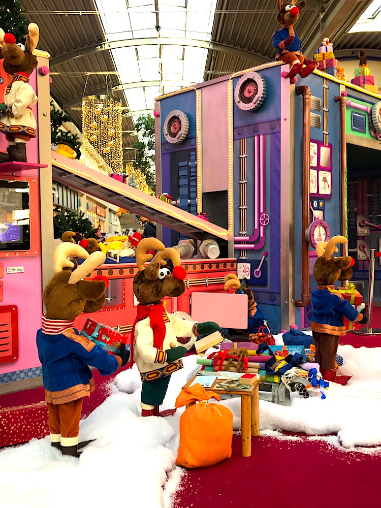 Rudis Rentiertrupp verpackt Weihnachtsgeschenke mit einer großen Maschine