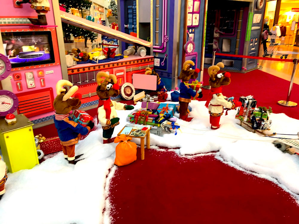 Rudis Rentiertrupp verpackt Weihnachtsgeschenke mit einer großen Maschine