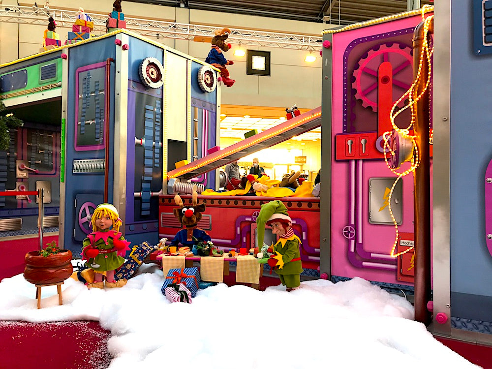 Rudis Rentiertrupp verpackt Weihnachtsgeschenke mit einer großen Maschine